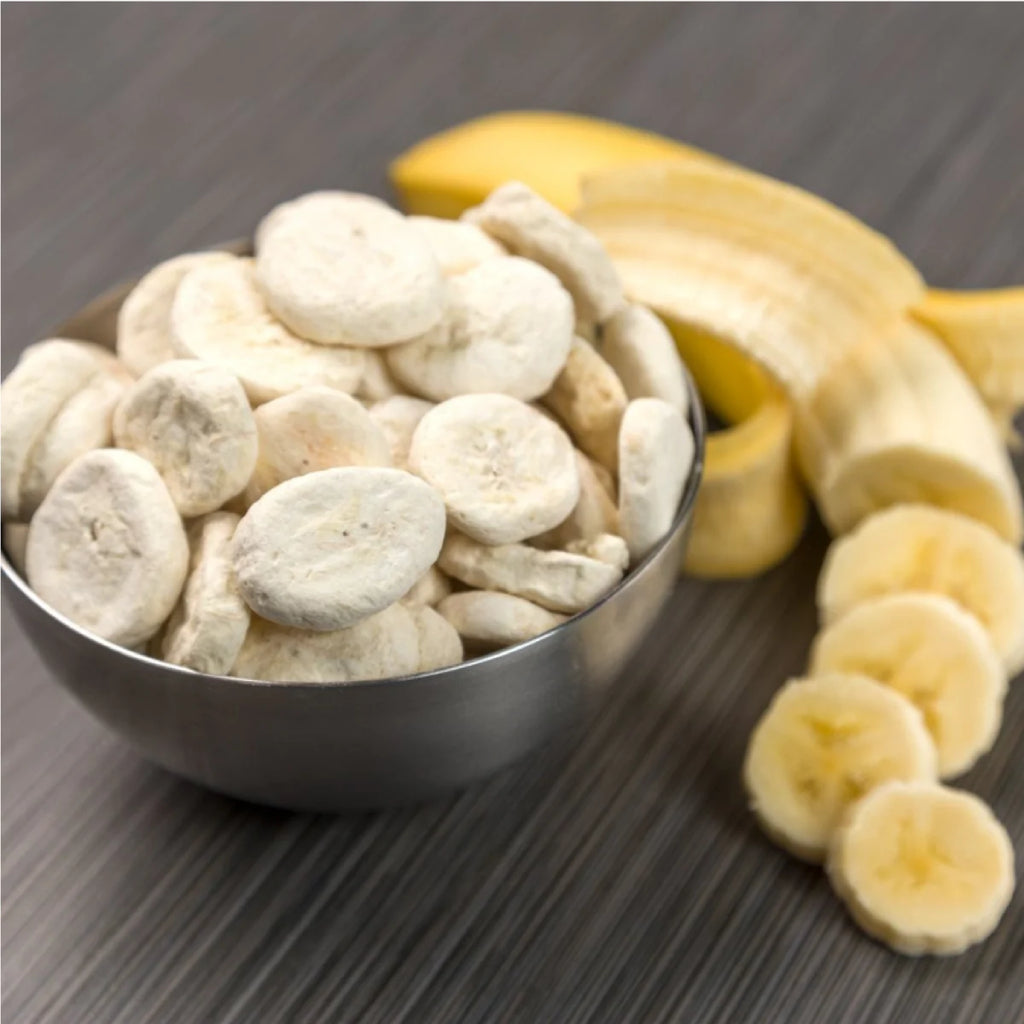 Nutristore Freeze Dried Bananas on a stainless steel bowl next to a fresh sliced banana