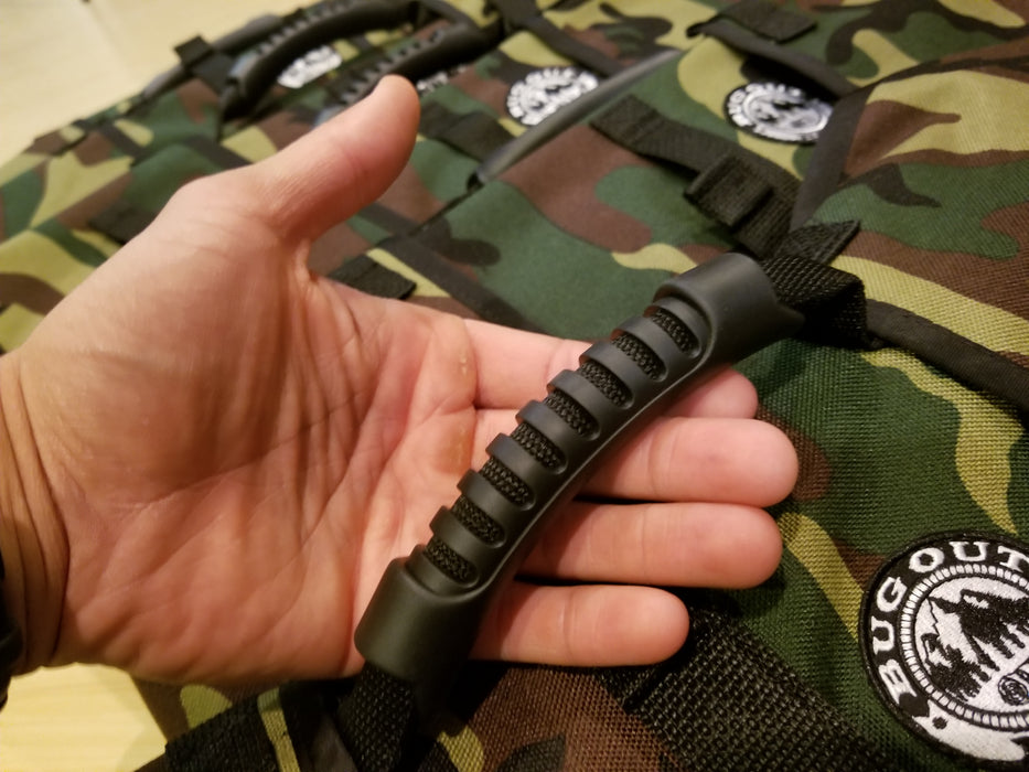 Hand holding a Forest Camo Bug Out Roll from the rubberized handle grip. The Bug out logo is seen on the bag in black and white design.