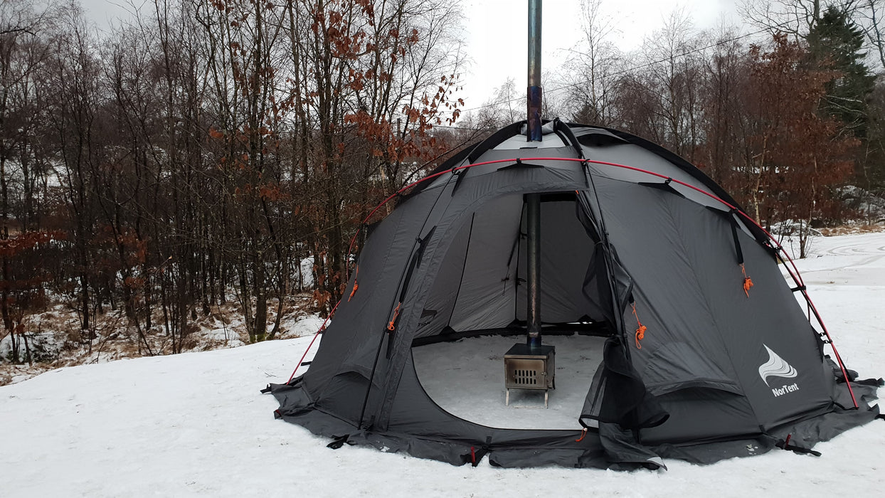 A small wood burning furnace is shown inside a Nortent Gamme 4 person tent with the chimney coming out of the tent top.