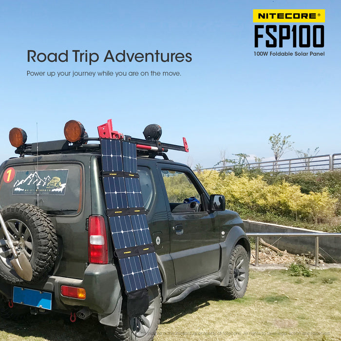 A Nitecore FSP100 flold out solar panel on the side of a forest green suv.