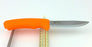 A orange Morakniv bushcraft knife balanced on two rulers on a white background.