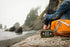 A girl relaxing and looking out on the beach during a foggy day with her orange hiking backpack and Goal zero Rock out 2 Speaker.