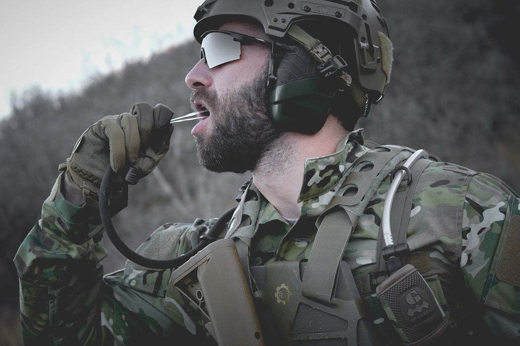 A soldier spraying water into his mouth using a pressurized hydration pack called 'The Rigger' from Geigerrig and Canadian prepper.