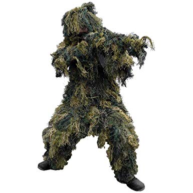 Person wearing the Bushline Outdoors Guillie Suit with balck boots and a concealed rifle on a white background.