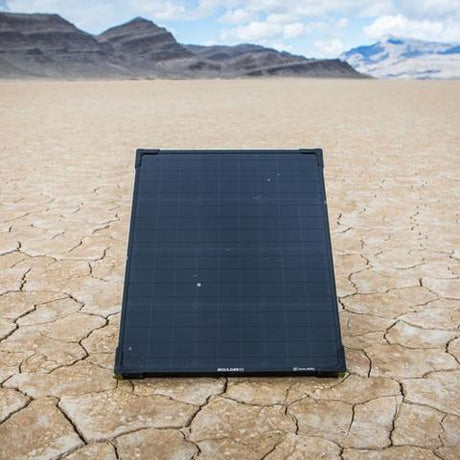 Goal Zero Boulder 50 Solar Panel set out to catch some solar rays in a dessert landscpae with mountains in the background.