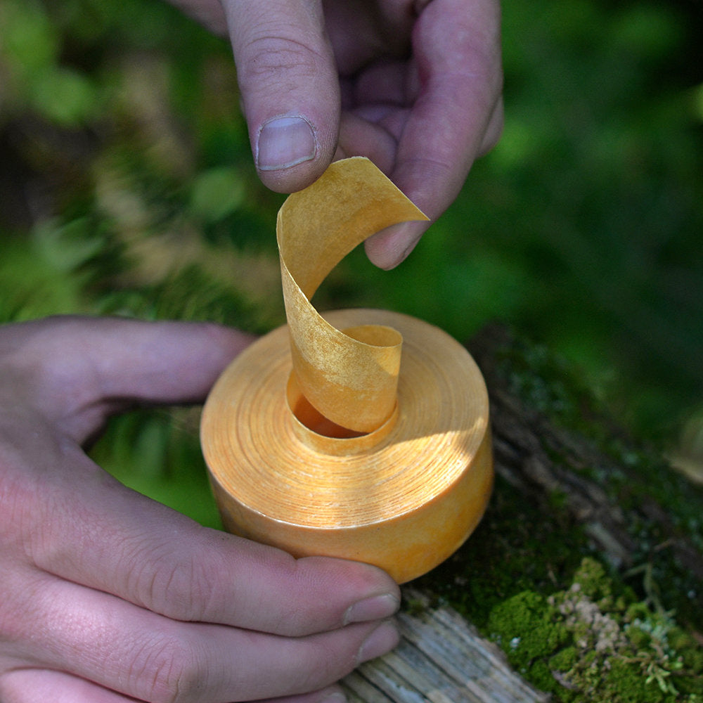 Person unraveling a fire strip roll to start a fire camping.