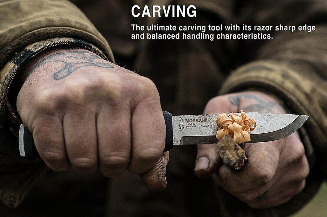 A man with tattoo's on his hands is shaving a piece of wood with a Morakniv Garberg knife. The description 'Carving, the ultimate carving tool with its razor sharp edge and balanced handling characteristics.