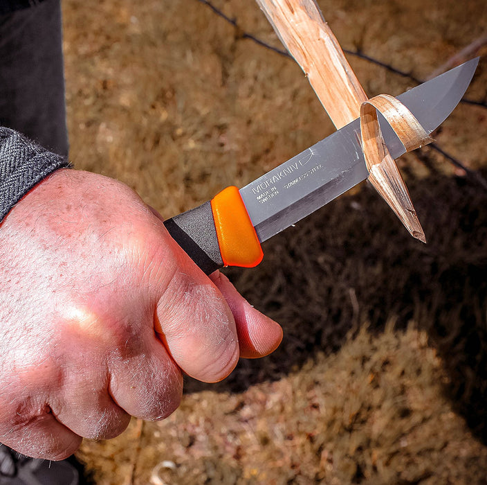 A Companion ranger knife being used to strip wood from a branch for fire kindling.