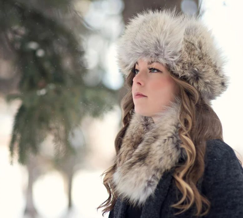 A woman with blue eyes and highlighted brown hair wearing a Coyote Fur Headband Hat in the winter.