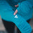 A triangular cut out of Gear Aid Reflective Tape on a cardinal blue zip up sweater sleeve.