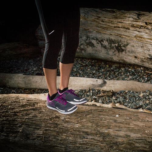 Gear Aid Reflective Patches on a womans shoes glowing in the dark at night on a shoreside.