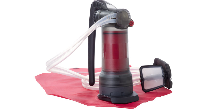 The MSR Guardian water purifying system on a red cloth. The filter is shown encased within the apparatus and the water grate on the end of the house.