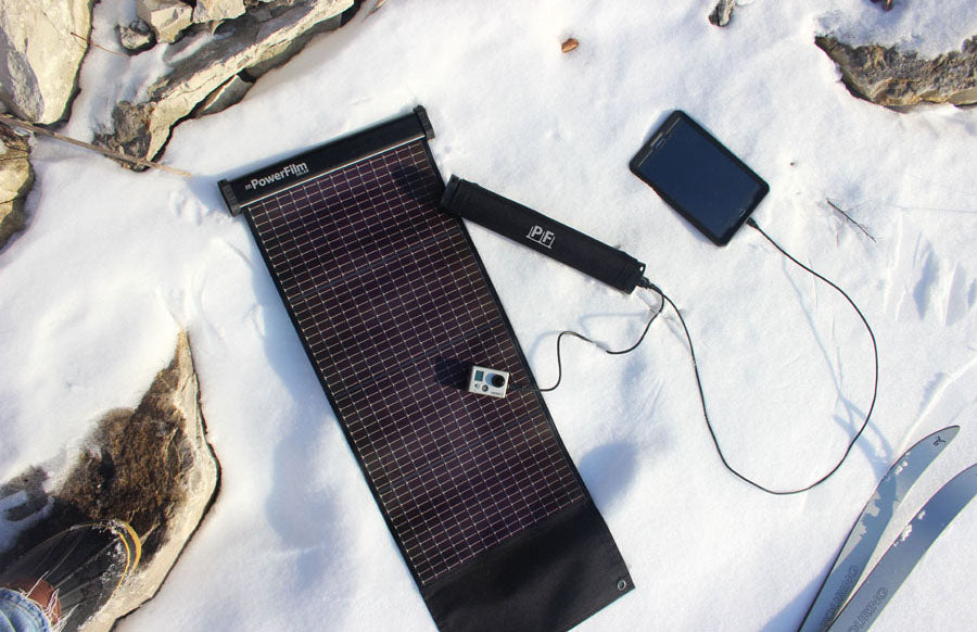 A Lightsaver Max Solar Power Film Strip charging a tablet and gopro in the snow.