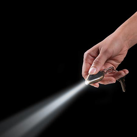 Person holding the Radiant rechargeable keychain microlight, the light beam is shooting forward.