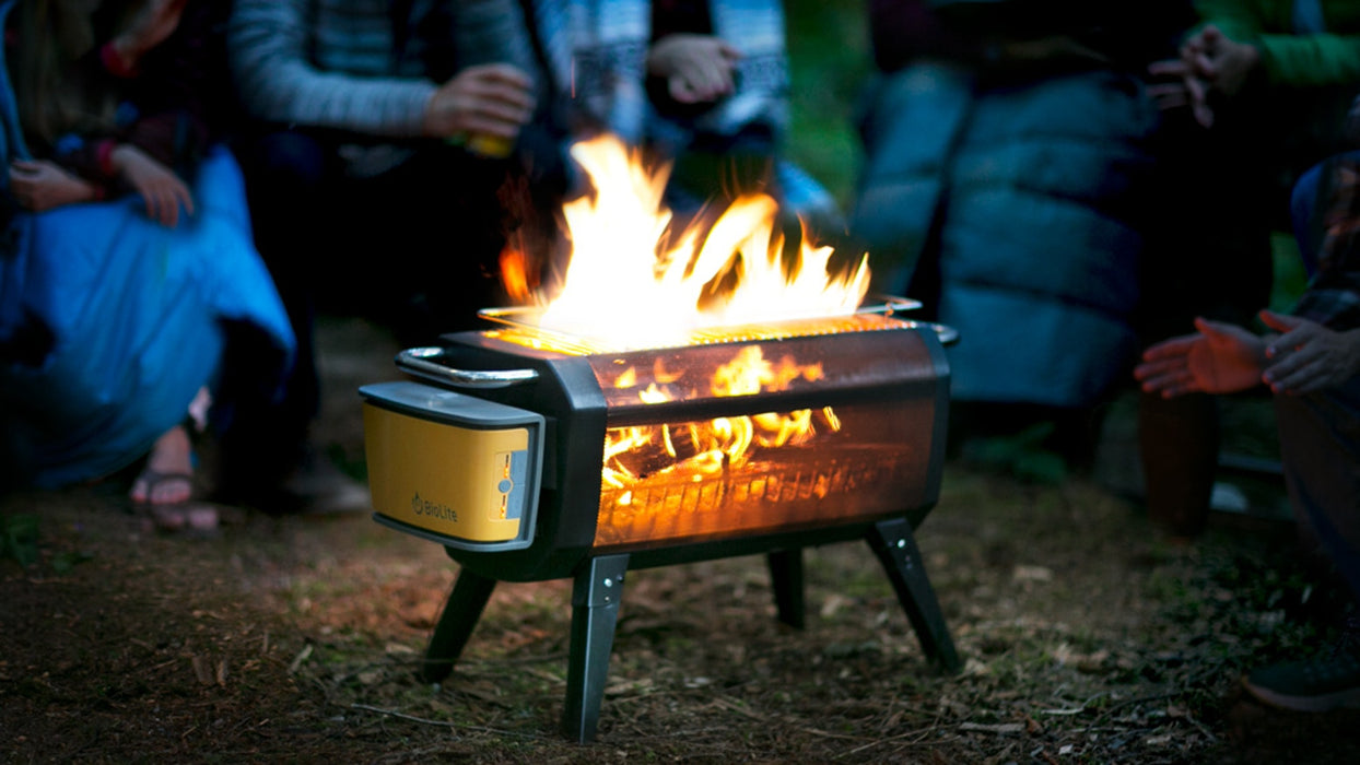 6 people camping with their hands out warming up on a cool summers night with the BioLite Firepit Smokeless Natural Fuel Pit.