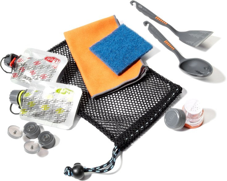GSI Outdoors Kitchen Essentials pack with a spatula, large cooking spoon, salt & pepper shakers, cleaning rag, drying towel, and two swappable condiment pouches on a white background.